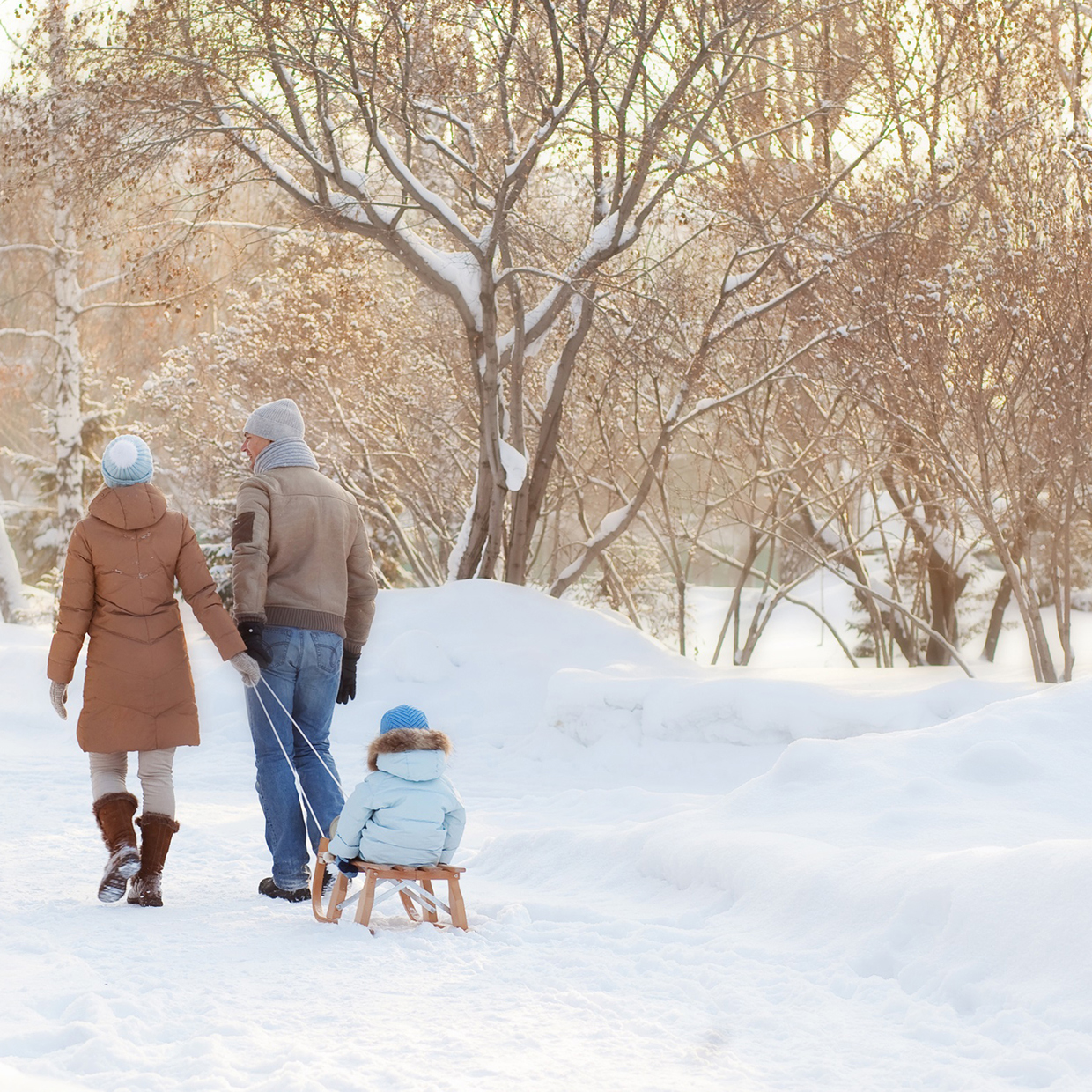 Mère, père et enfant en traîneau sur un chemin enneigé